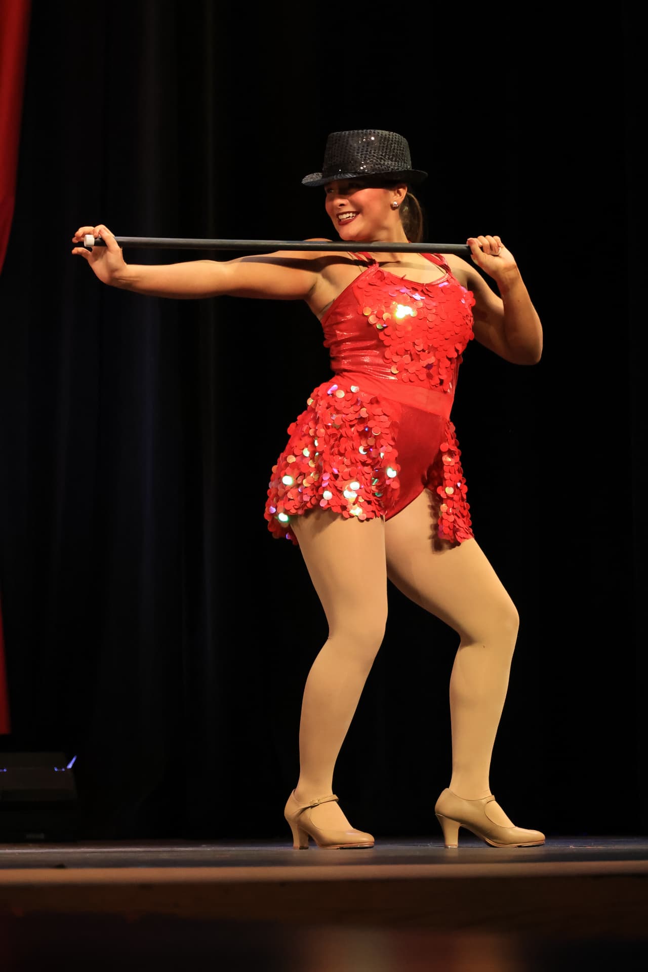 Dancer in a sparkling red sequin costume with top hat performing with a cane