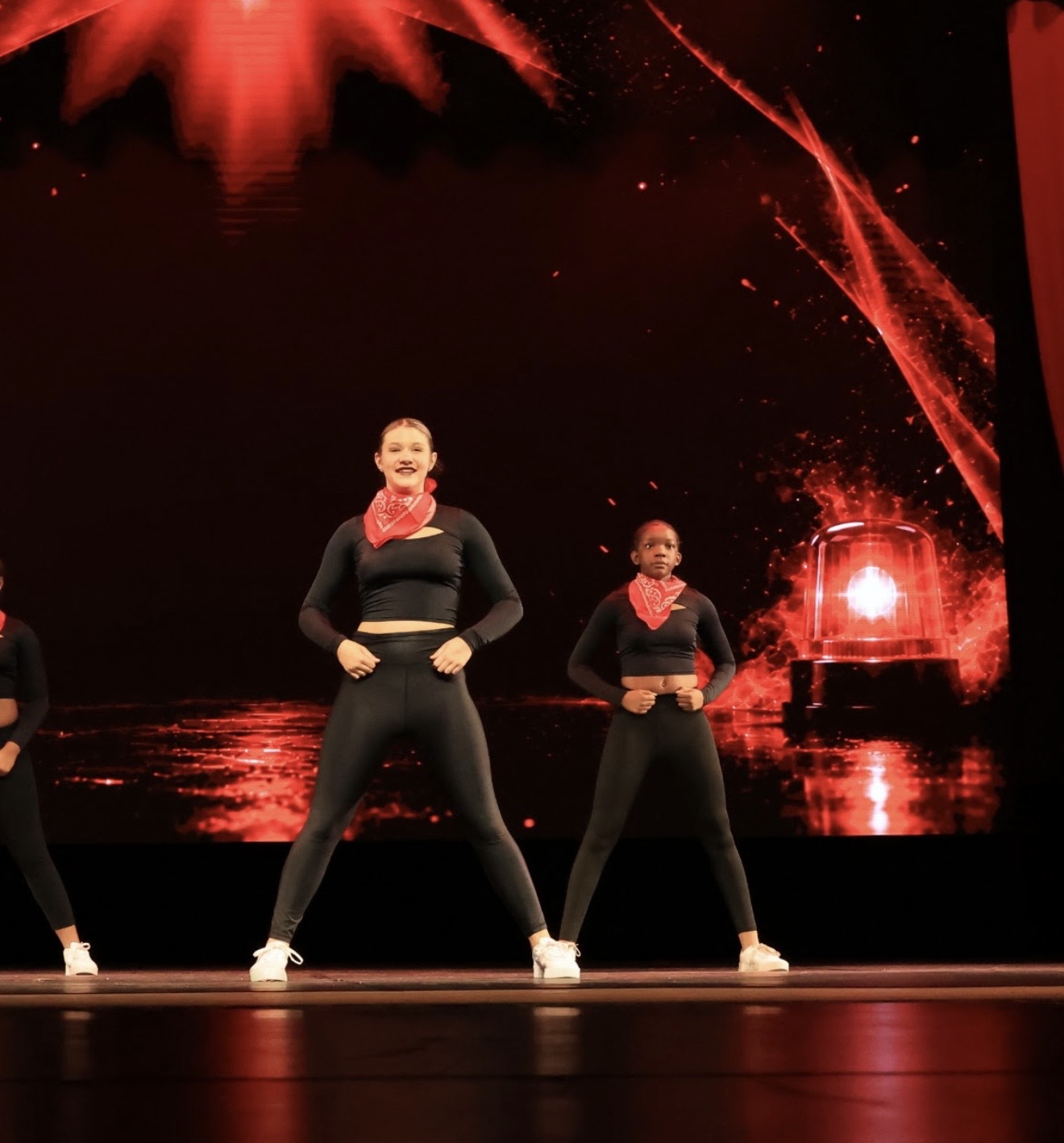 The Crew dancers in black outfits with red bandanas performing on stage under red lights
