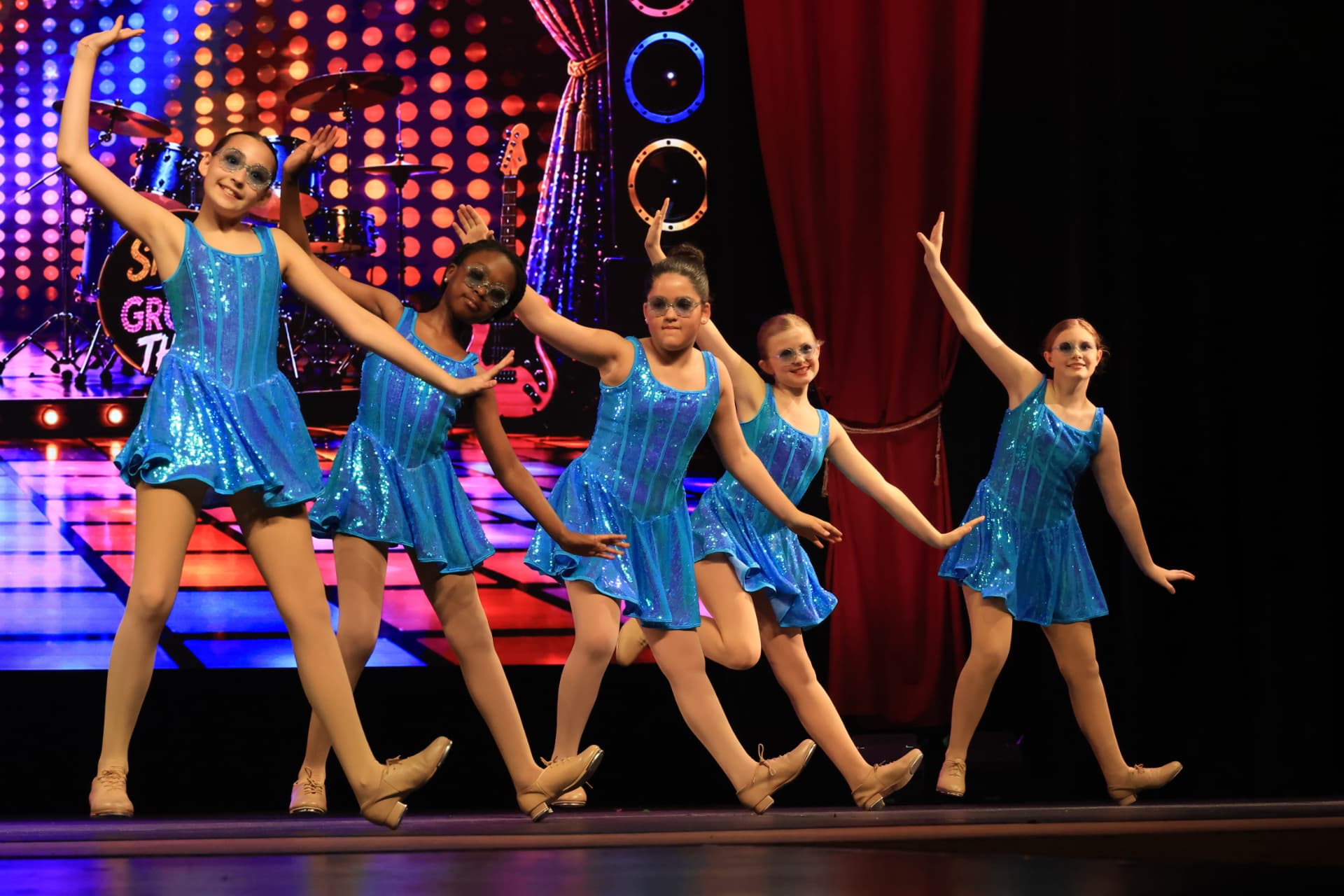 Five Company dancers in sparkling blue sequin dresses striking a pose